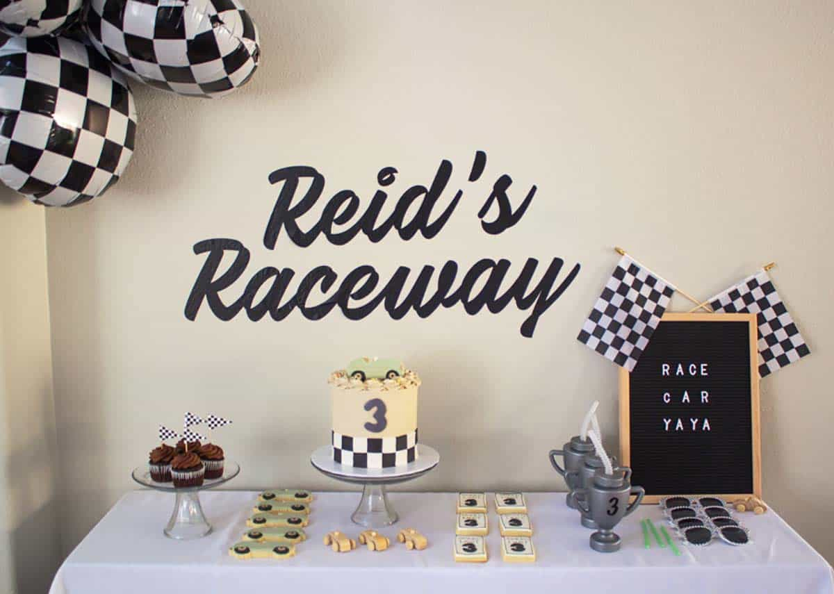 Race car birthday dessert table with a "Reid's Raceway" vinyl decal backdrop